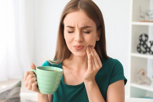 woman in a dental pain while holding a cup